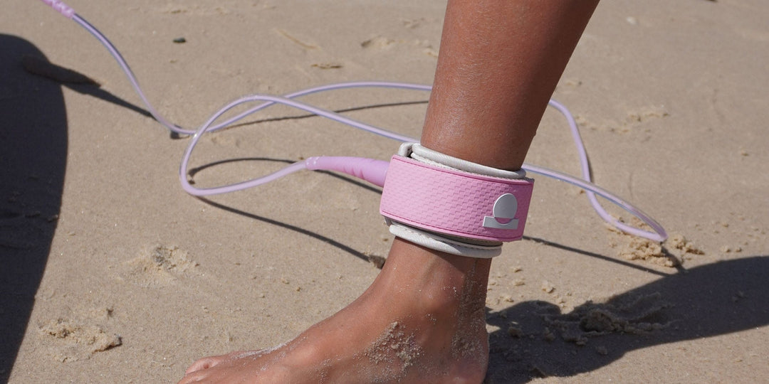 Pink Summer vibes surf leash cuff strapped on an ankle on the sand