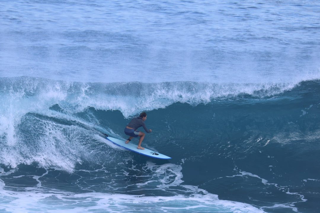 Surfer riding a blue Summer vibes Discus along the wave face