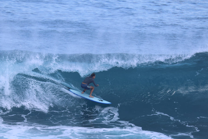 Surfer riding a blue Summer vibes Discus along the wave face